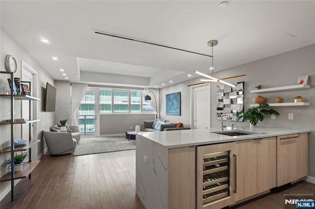 kitchen featuring beverage cooler, a sink, open floor plan, and light brown cabinetry