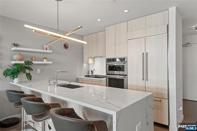 kitchen featuring modern cabinets, a breakfast bar area, stainless steel appliances, and a sink