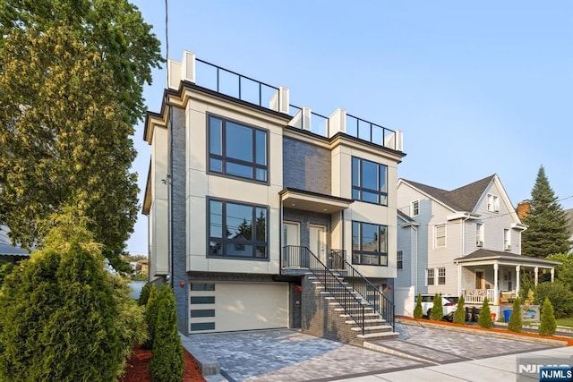 view of front facade featuring an attached garage, stairway, decorative driveway, and stucco siding