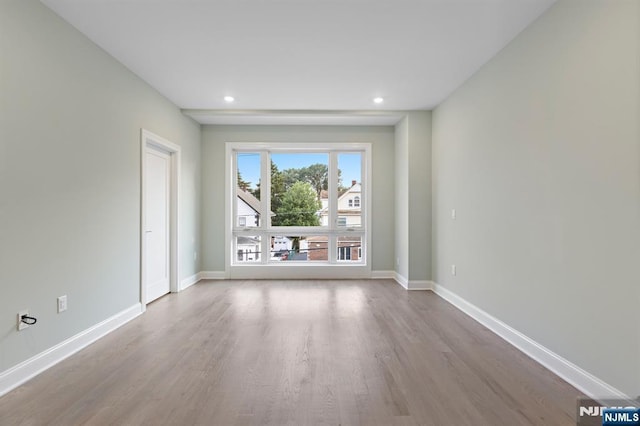 spare room featuring recessed lighting, wood finished floors, and baseboards