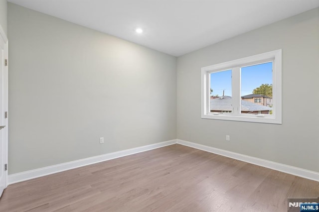 spare room featuring light wood-style floors, recessed lighting, and baseboards