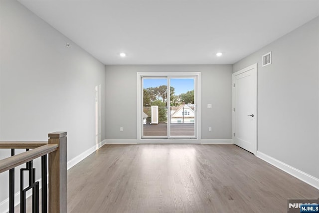 unfurnished room with visible vents, baseboards, and wood finished floors