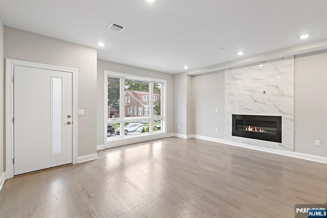 unfurnished living room featuring a fireplace, visible vents, wood finished floors, and recessed lighting