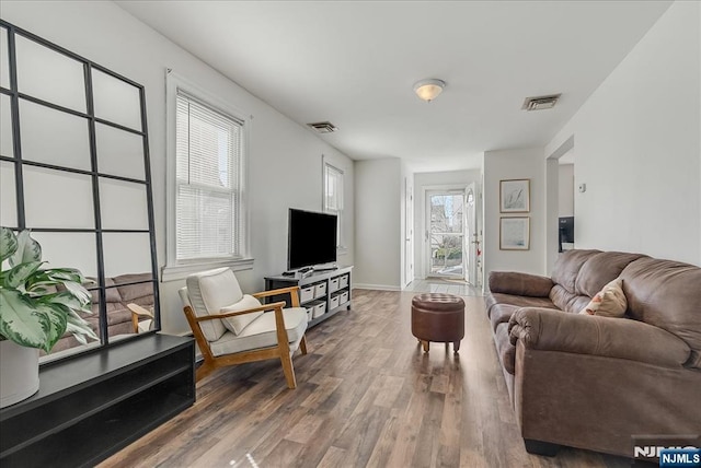 living room featuring visible vents, baseboards, and wood finished floors