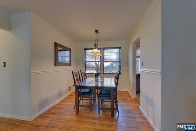 dining room with ornamental molding, hardwood / wood-style floors, and baseboards