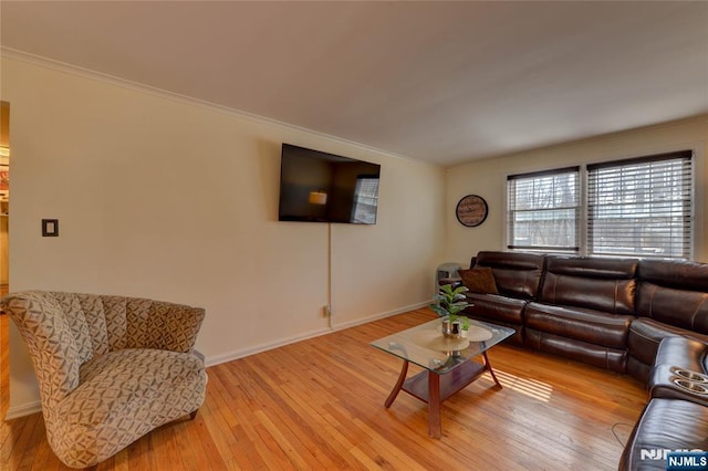 living area with ornamental molding, hardwood / wood-style flooring, and baseboards