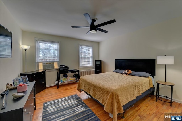 bedroom with radiator heating unit, light wood-style flooring, and a ceiling fan