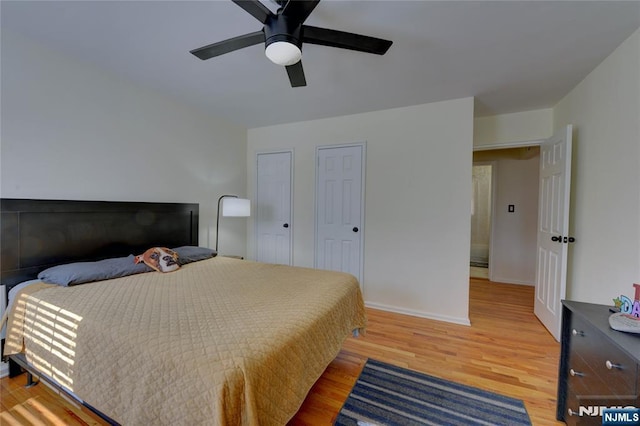 bedroom featuring multiple closets, ceiling fan, baseboards, and wood finished floors