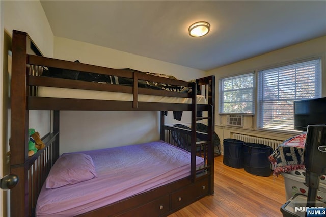 bedroom featuring radiator heating unit, cooling unit, and wood finished floors