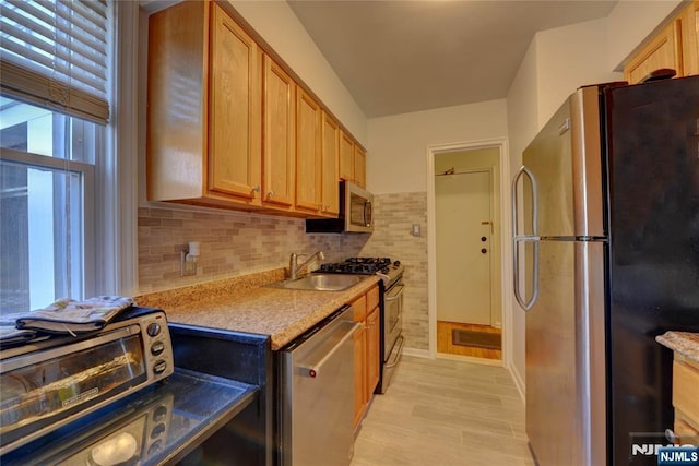 kitchen featuring a toaster, appliances with stainless steel finishes, light countertops, light wood-style floors, and a sink