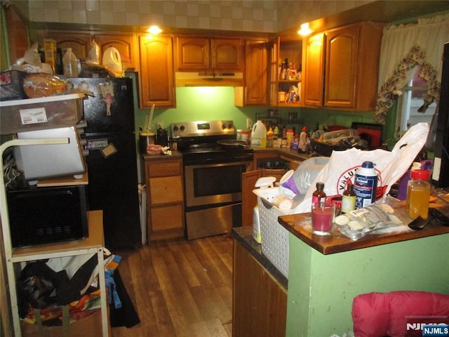 kitchen with under cabinet range hood, brown cabinets, dark wood-type flooring, and stainless steel range with electric cooktop