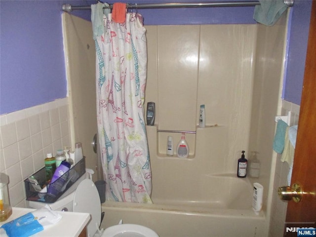 bathroom with toilet, shower / bathtub combination with curtain, and tile walls