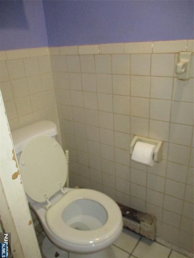 bathroom featuring tile patterned flooring, toilet, and tile walls