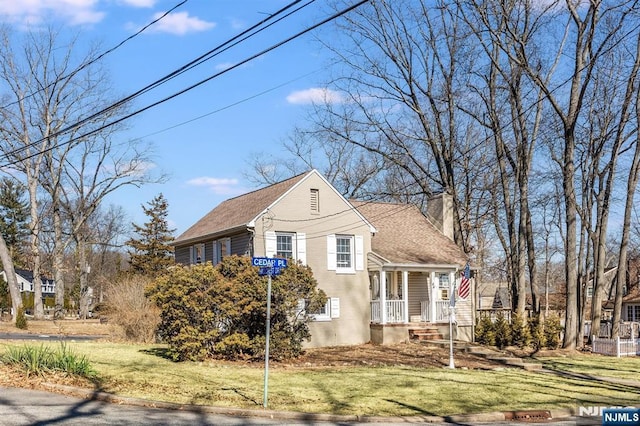 view of front of property with a front lawn, a chimney, and a shingled roof