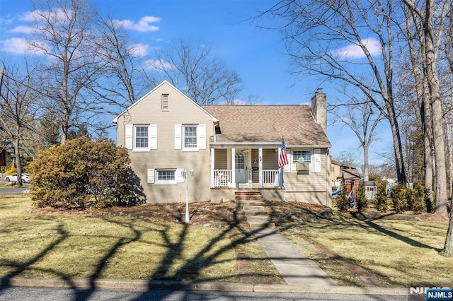 tri-level home with covered porch, roof with shingles, a chimney, and a front lawn