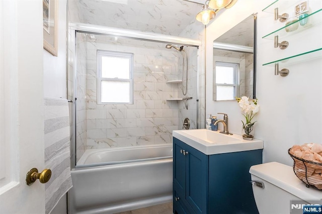 full bath featuring toilet, shower / bath combination with glass door, and vanity