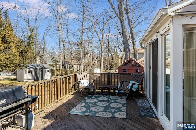 wooden deck featuring a storage unit, grilling area, and an outdoor structure