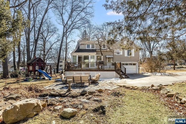 view of front facade featuring a garage, playground community, driveway, and a wooden deck