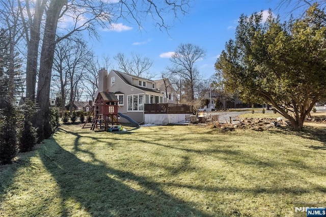 view of yard with a sunroom, a playground, and a wooden deck