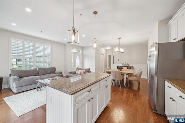 kitchen featuring dark wood-style flooring, freestanding refrigerator, open floor plan, white cabinetry, and light stone countertops