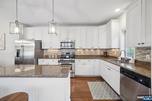 kitchen featuring appliances with stainless steel finishes, white cabinets, a sink, and tasteful backsplash