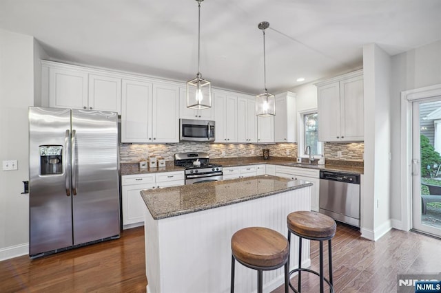 kitchen with stainless steel appliances, a kitchen island, a sink, and white cabinetry