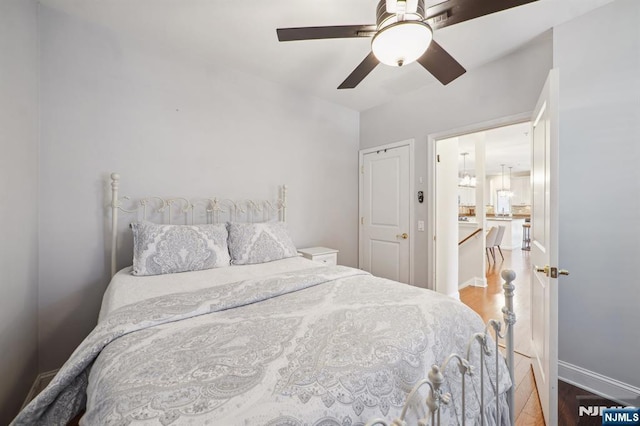 bedroom featuring a ceiling fan, baseboards, and wood finished floors