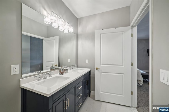 ensuite bathroom with connected bathroom, marble finish floor, a sink, and double vanity