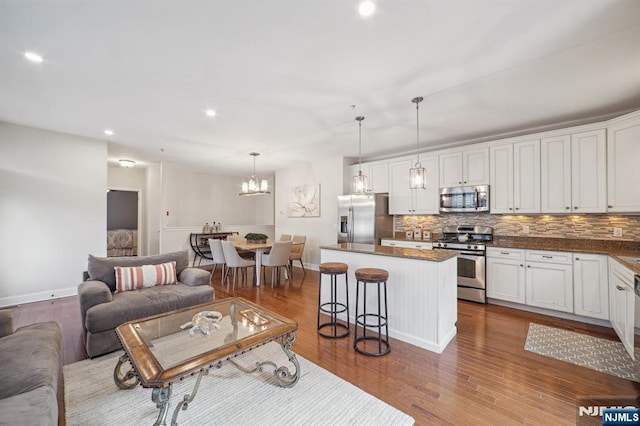 living room featuring baseboards, a chandelier, wood finished floors, and recessed lighting