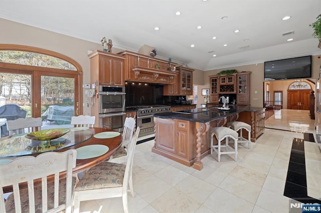 kitchen featuring recessed lighting, stainless steel appliances, a kitchen breakfast bar, dark countertops, and glass insert cabinets