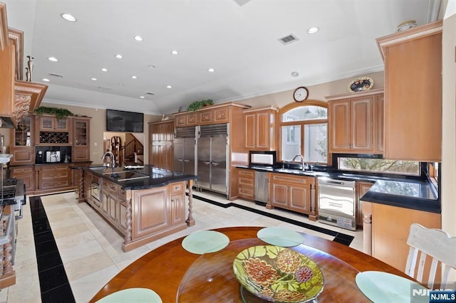 kitchen with dark countertops, ornamental molding, a sink, and recessed lighting