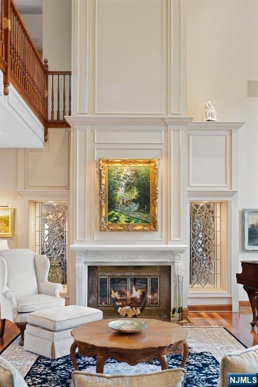 interior space featuring a towering ceiling, a fireplace with flush hearth, and wood finished floors