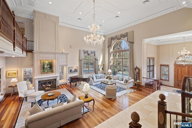 living area with a towering ceiling, an inviting chandelier, and a large fireplace