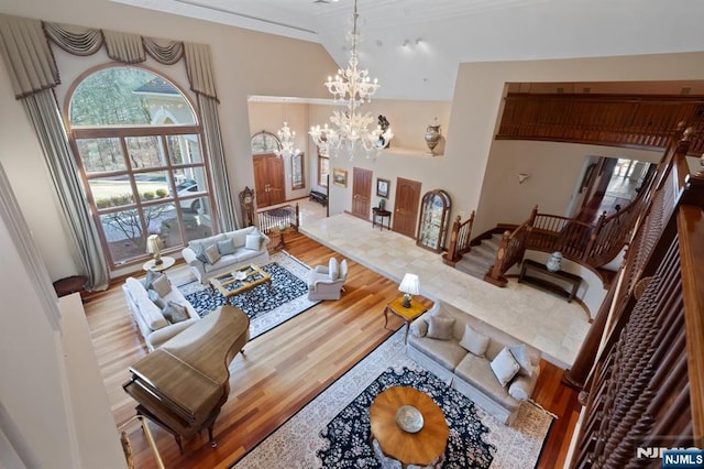 living room featuring high vaulted ceiling, an inviting chandelier, stairway, and wood finished floors