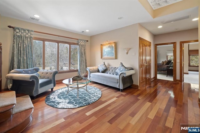 living area with visible vents, baseboards, and wood finished floors