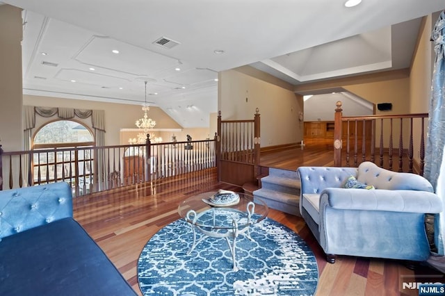 living area featuring a chandelier, lofted ceiling, visible vents, and wood finished floors