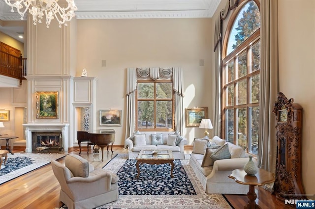 interior space with a towering ceiling, plenty of natural light, wood finished floors, and a glass covered fireplace