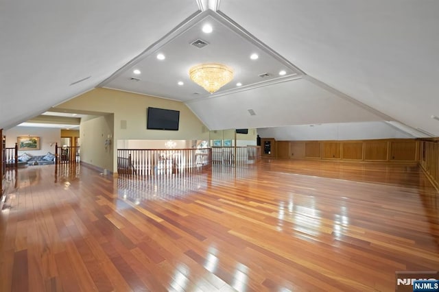 additional living space with vaulted ceiling, wood-type flooring, visible vents, and an inviting chandelier