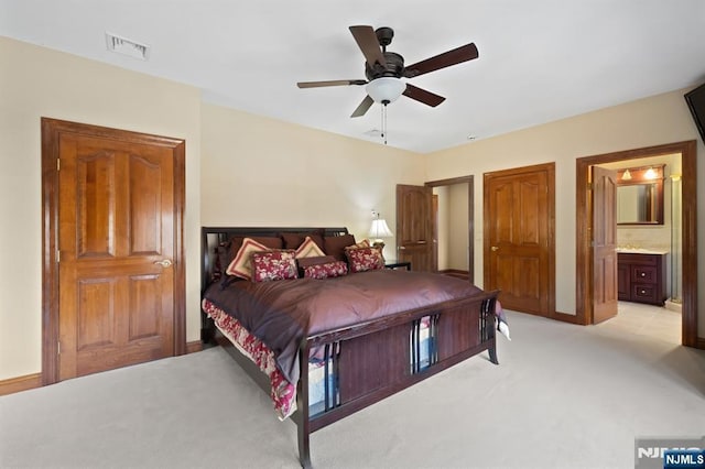 bedroom featuring ceiling fan, visible vents, ensuite bathroom, and light colored carpet