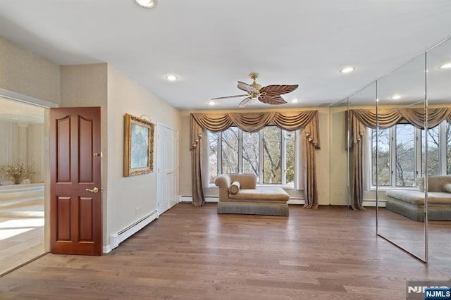 unfurnished room with a baseboard heating unit, wood finished floors, a ceiling fan, and recessed lighting