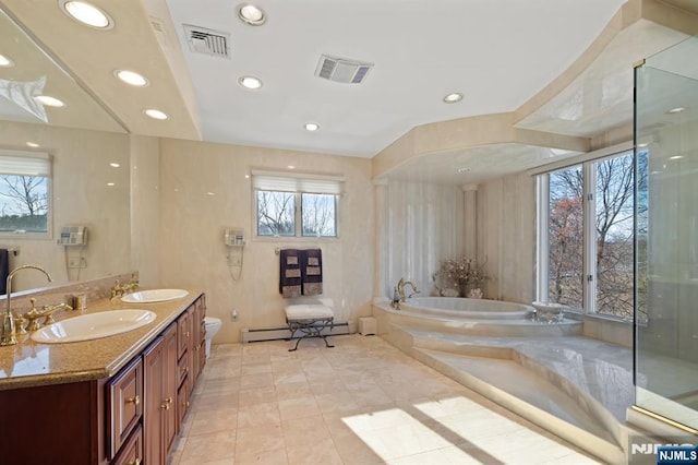 bathroom featuring a baseboard radiator, visible vents, a sink, and a garden tub