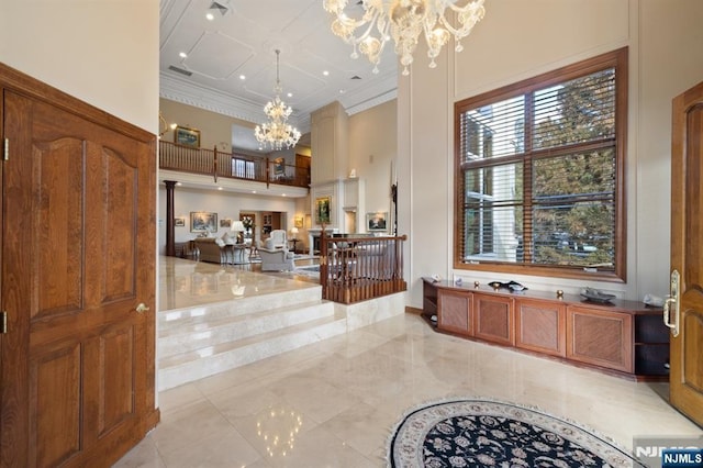 foyer featuring a towering ceiling, visible vents, a chandelier, and crown molding