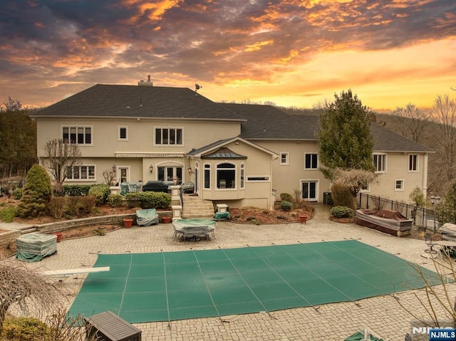 rear view of house with a fenced in pool, a chimney, stucco siding, a patio area, and fence