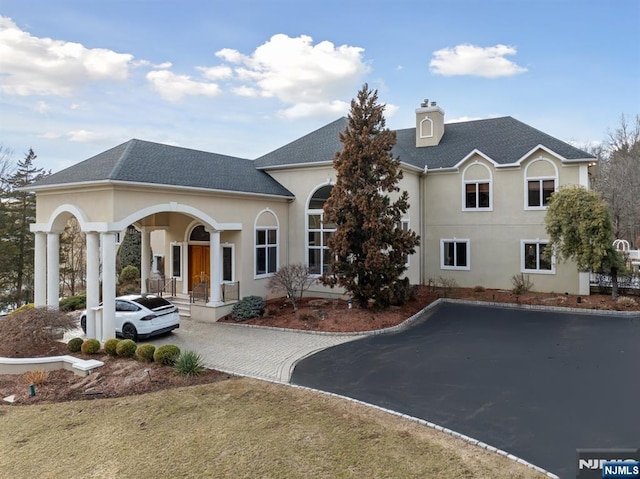 view of front of house with driveway, a shingled roof, and stucco siding