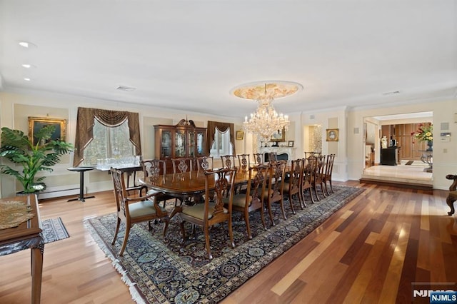 dining space with a notable chandelier, light wood-style flooring, baseboards, and crown molding