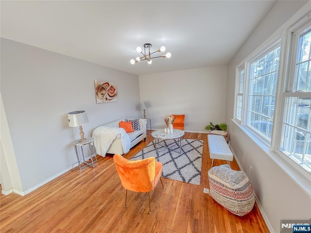 sitting room featuring a chandelier, baseboards, and wood finished floors