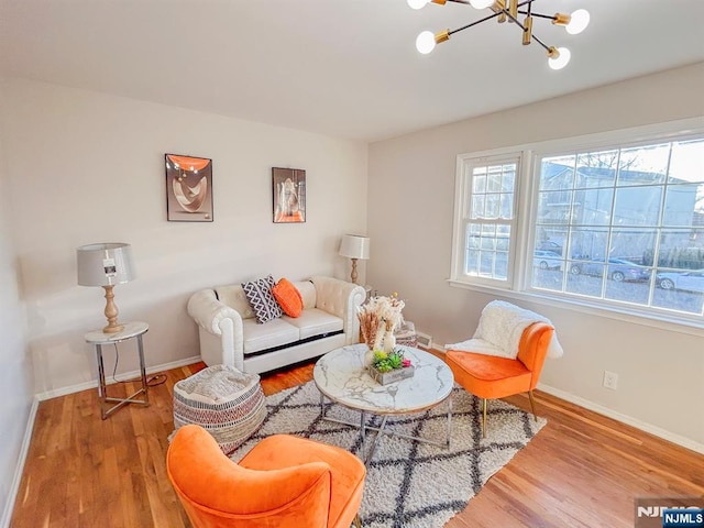 living room featuring a chandelier, baseboards, and wood finished floors