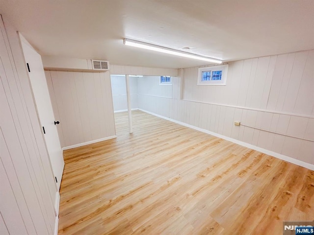 basement featuring visible vents, baseboards, and wood finished floors