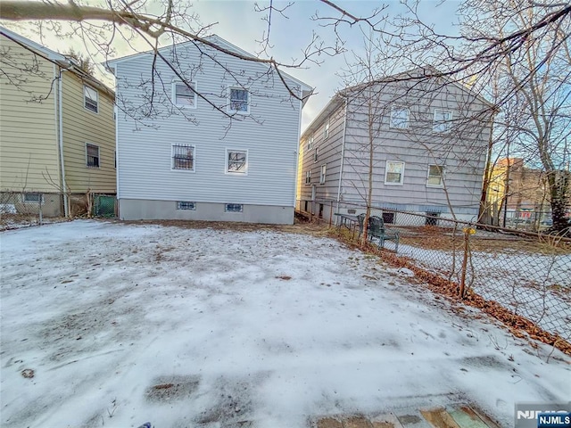 snow covered rear of property featuring fence