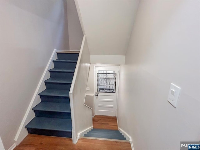 staircase featuring baseboards and wood finished floors